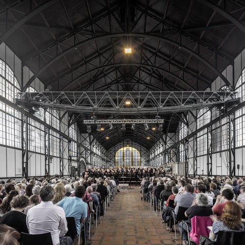 Menschen sitzen auf Stuhlreihen in der Maschinenhalle des LWL-Museums Zeche Zollern.